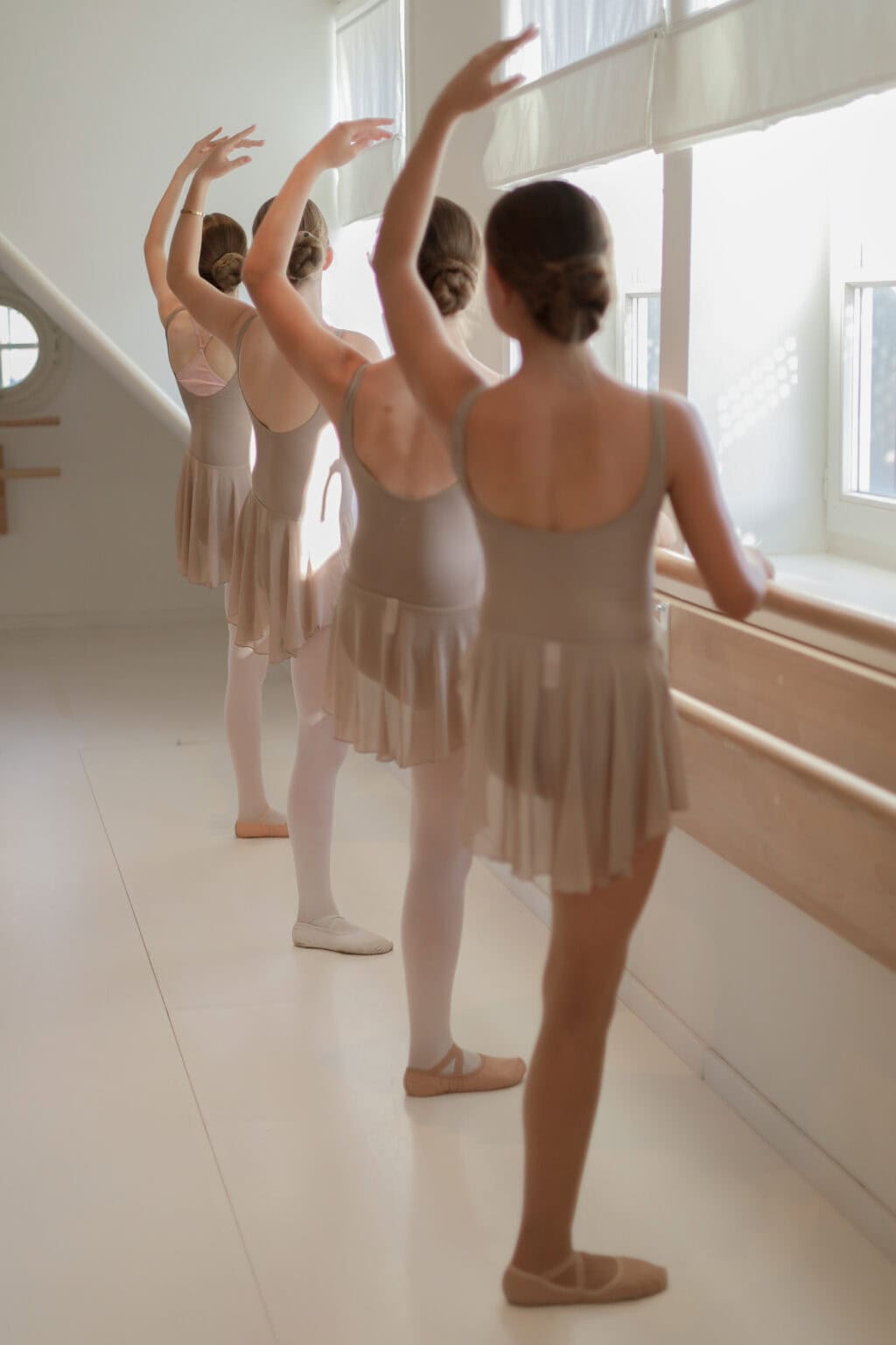 Jugendliche Ballettschülerinnen an der Stange mit erhobenem Arm