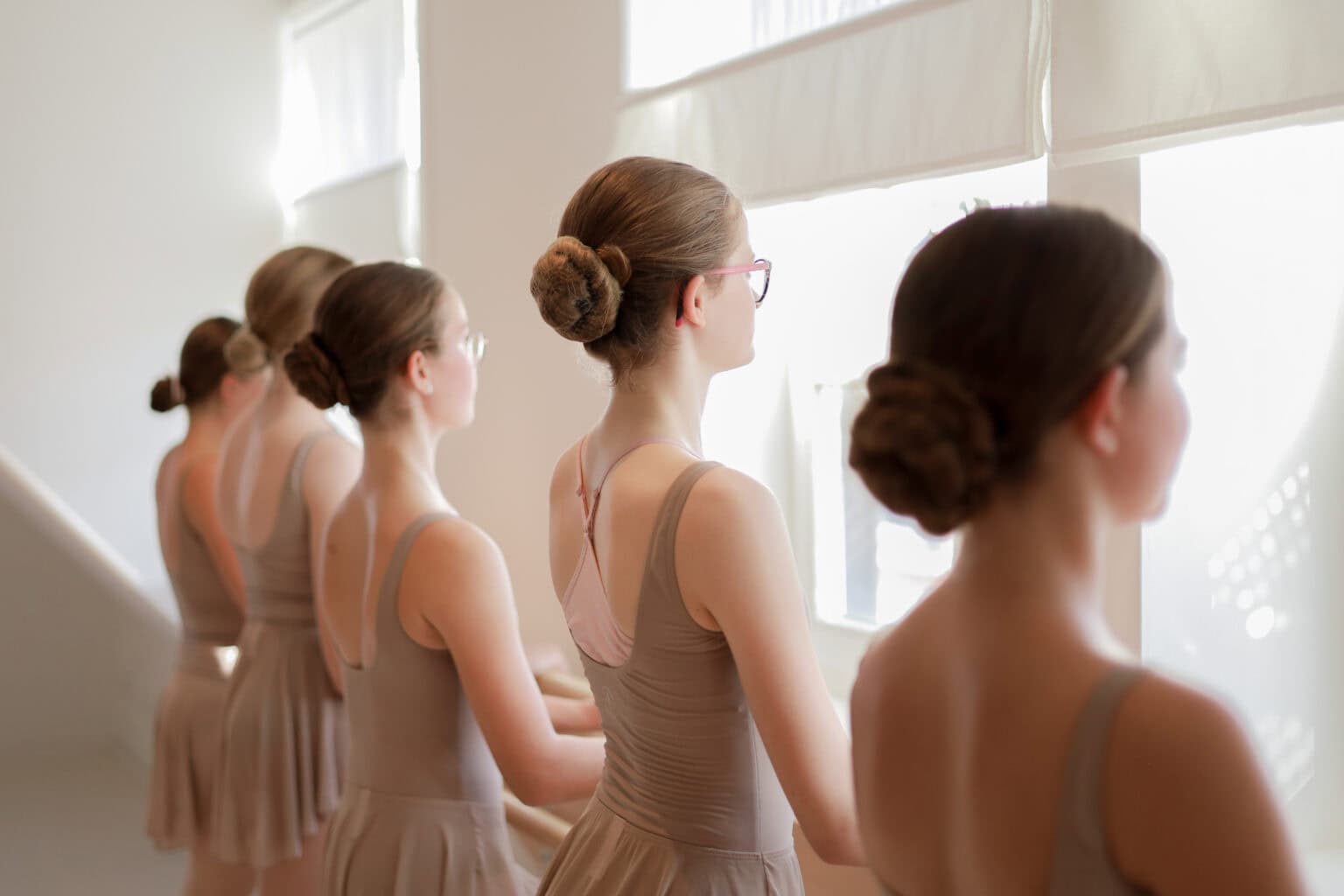 Gruppe jugendlicher Ballettschülerinnen im Unterricht am Fenster